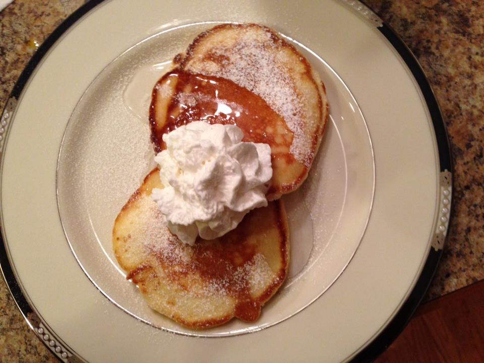 image of pancakes dusted with powdered sugar with whipped cream on them